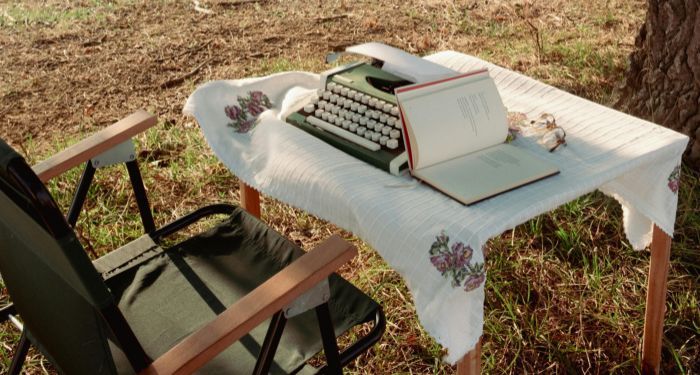 a typewriter and a book on a table outside.jpg.optimal