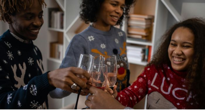 three Black people of varying skin tones smiling and clinking champagne glasses.jpg.optimal