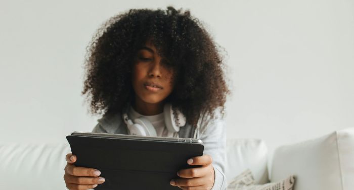 brown skinned Black woman with fro looking at a tablet.jpg.optimal