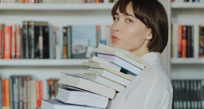 fair skinned Asian woman with a bob holding a stack of books.jpg.optimal