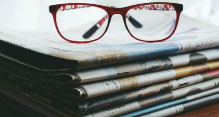 red eyeglasses on a stack of newspapers.jpg.optimal